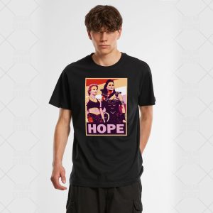 Un jeune homme portant un t-shirt noir avec un graphique de style pop art représentant deux femmes debout ensemble au-dessus du mot HOPE en lettres grasses, célébrant la fierté LGBTQIA+.