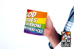 Une personne tient une tasse aux couleurs de l'arc-en-ciel avec les mots "God loves everyone motherf*cker !" (Dieu aime tout le monde, connard). Le logo "Break the Closet" avec une licorne apparaît dans le coin inférieur droit, célébrant la fierté LGBTQIA+ et la joie queer.