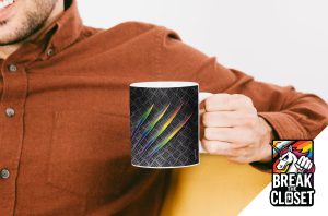 Une personne vêtue d'une chemise de couleur rouille tient une tasse avec des marques de griffes arc-en-ciel sur un motif sombre. Dans le coin, un logo "Break the Closet" célèbre la fierté LGBTQIA+, avec une licorne, des couleurs arc-en-ciel et un poing brisant une porte.