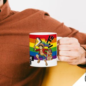 Une personne vêtue d'une chemise brune tient une tasse avec des personnages d'anime, sur fond de drapeau de la fierté arc-en-ciel et d'un logo LGBT "Break the Closet" représentant une licorne et un drapeau arc-en-ciel dans le coin inférieur droit.