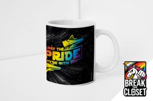 Un mug blanc présente des vaisseaux spatiaux colorés et la phrase "May the Pride Be With You" en lettres arc-en-ciel sur un fond étoilé. Dans le coin, le logo d'une licorne est accompagné de l'inscription "Break the Closet", qui célèbre la fierté queer et LGBTQIA+.
