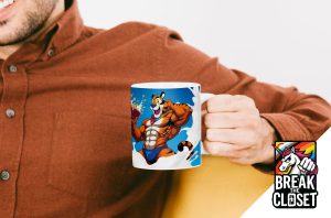 Une personne vêtue d'une chemise de couleur rouille tient un mug représentant un tigre de dessin animé musclé en maillot de bain. Dans le coin inférieur droit, un logo de licorne aux couleurs de l'arc-en-ciel affiche le texte BREAK THE CLOSET, célébrant la fierté queer et LGBT.