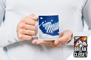Une personne vêtue d'un pull léger tient une tasse avec un motif Extra Milk bleu et blanc. Dans le coin, un logo coloré de licorne "Break the Closet" célèbre la fierté LGBTQIA+.