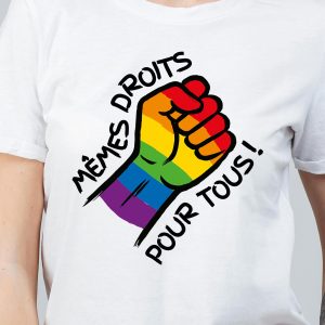 Une personne porte une chemise blanche avec un poing aux couleurs de l'arc-en-ciel et le texte français "Mêmes droits pour tous", soutenant fièrement l'égalité LGBTQIA+.