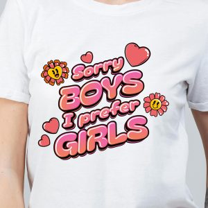 Une personne porte un t-shirt blanc avec un texte coloré et ludique : "Sorry boys, I prefer girls" (Désolé les garçons, je préfère les filles), entouré de cœurs de dessins animés et de fleurs souriantes - parfait pour montrer la fierté LGBTQIA+.