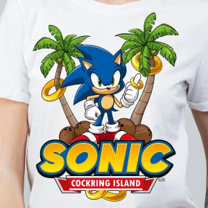 Un t-shirt représente Sonic le hérisson debout entre deux palmiers avec des anneaux d'or et des noix de coco, au-dessus d'un texte jaune gras indiquant SONIC et d'une bannière rouge indiquant COCKRING ISLAND, célébrant le plaisir queer dans un style résolument rétro.
