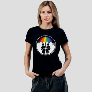 Une femme porte un t-shirt noir représentant deux personnages sous un parapluie arc-en-ciel, unis par les gouttes de pluie qui tombent, célébrant la fierté et l'unité des LGBT.