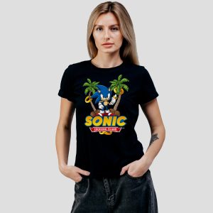 Une femme portant un T-shirt noir avec un graphique de Sonic le hérisson debout entre deux palmiers, tenant des anneaux d'or, et le texte Sonic Cokering Island - parfait pour exprimer votre fierté queer avec un style ludique et nostalgique.