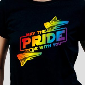 Une personne porte une chemise noire avec un texte coloré indiquant "May the PRIDE be with you", avec des dégradés d'arc-en-ciel, des illustrations de chasseurs d'étoiles et un clin d'œil à la fierté LGBT.