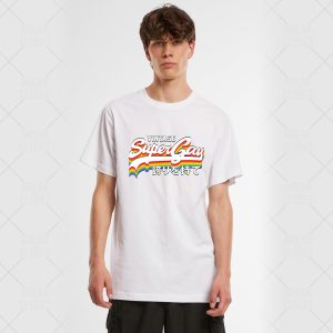 Un jeune homme se tient debout sur un fond uni et porte un T-shirt blanc sur lequel on peut lire Vintage Super Gay avec un arc-en-ciel et un texte en japonais en dessous, exprimant fièrement son identité queer.