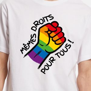 Un t-shirt représente un poing levé coloré avec le drapeau arc-en-ciel de la Fierté, symbolisant la fierté LGBTQIA+. Autour du poing, un texte en français indique "Mêmes droits pour tous !", ce qui signifie "Equal rights for all !" en anglais.
