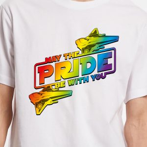 Ce t-shirt blanc comporte un texte aux couleurs de l'arc-en-ciel indiquant May the Pride Be With You, célébrant la fierté LGBT, ainsi que deux vaisseaux spatiaux arc-en-ciel inspirés de Star Wars de part et d'autre du mot "Pride" (fierté).