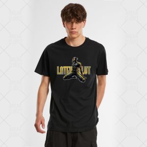 Un jeune homme aux cheveux bruns ondulés porte le Latex Slut - T-Shirt Unisexe, avec une panthère agenouillée illustrée et le texte jaune en gras "LATER CULT", mettant en valeur le style queer sur un fond blanc uni.